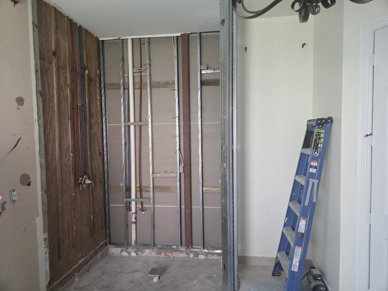 Bathroom under construction with exposed framing and plumbing