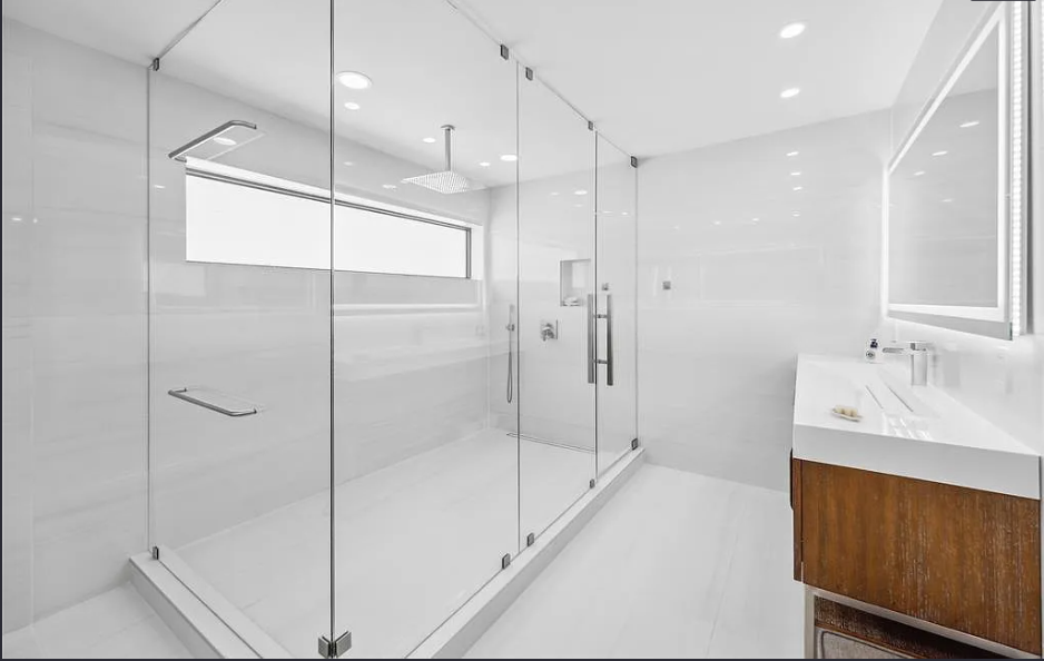 White tiled bathroom with a glass shower and wood vanity