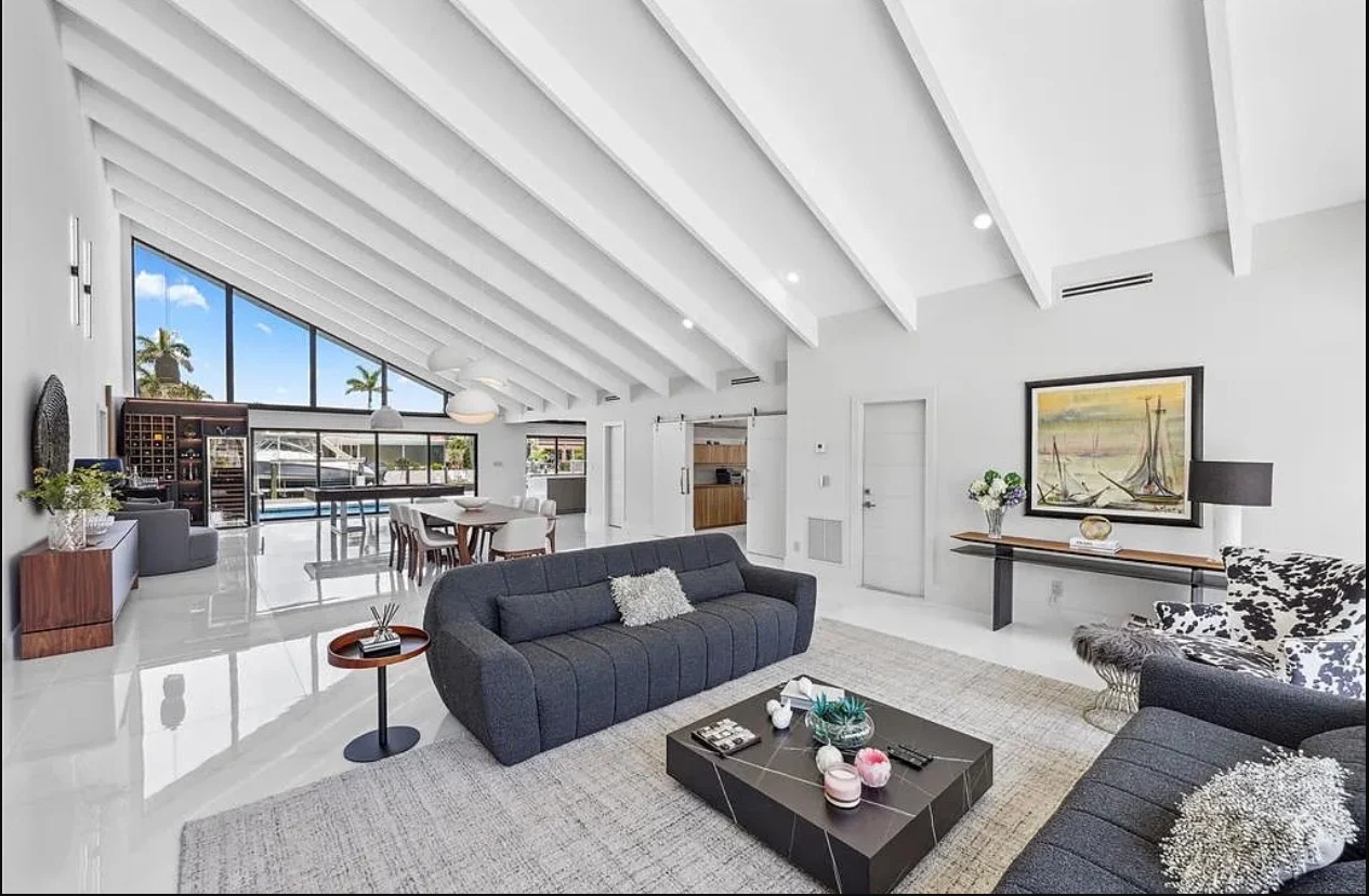 Finished open living and dining area with white beams and dark seating