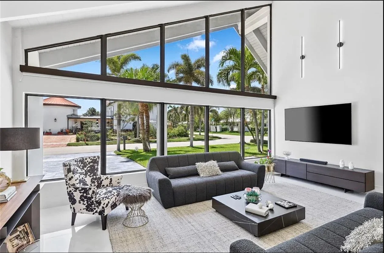 Renovated living room with tall windows overlooking the pool
