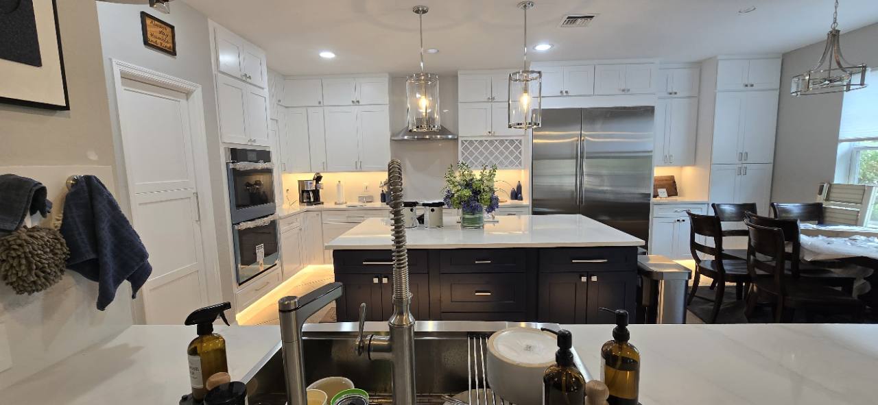 White cabinetry, a navy island, and warm accent lighting in a renovated kitchen