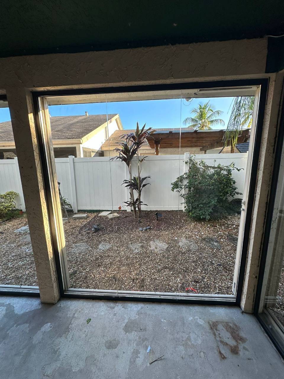 Patio glass panel detail with a garden view and unfinished surrounding surfaces