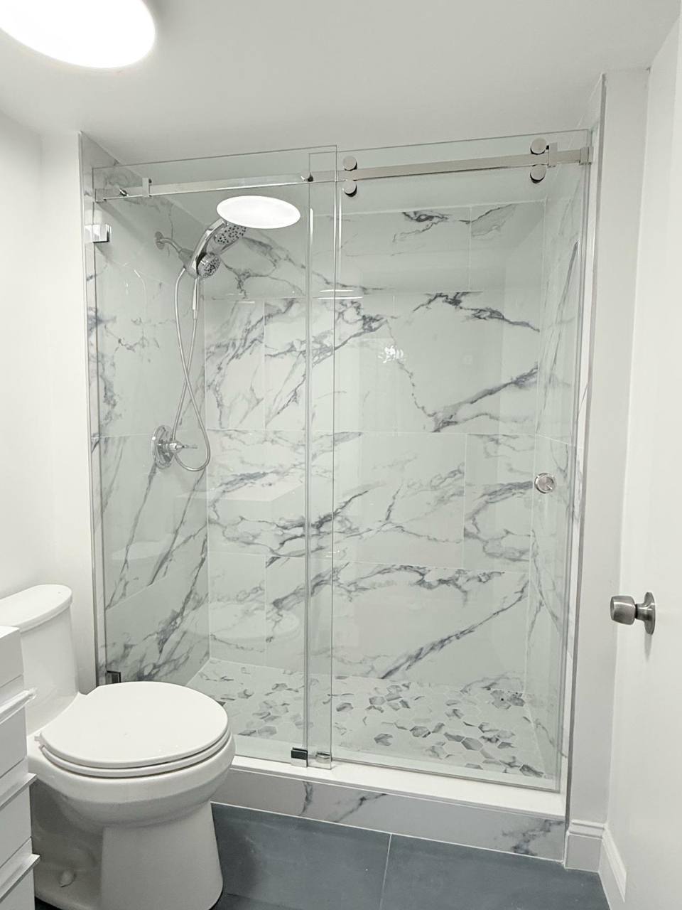 Sliding glass shower doors, veined tile, and a mosaic floor