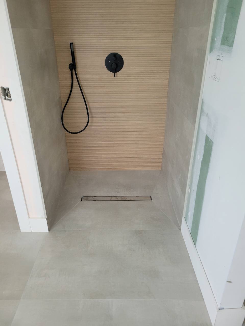 Close view of shower floor tile and a linear drain during installation