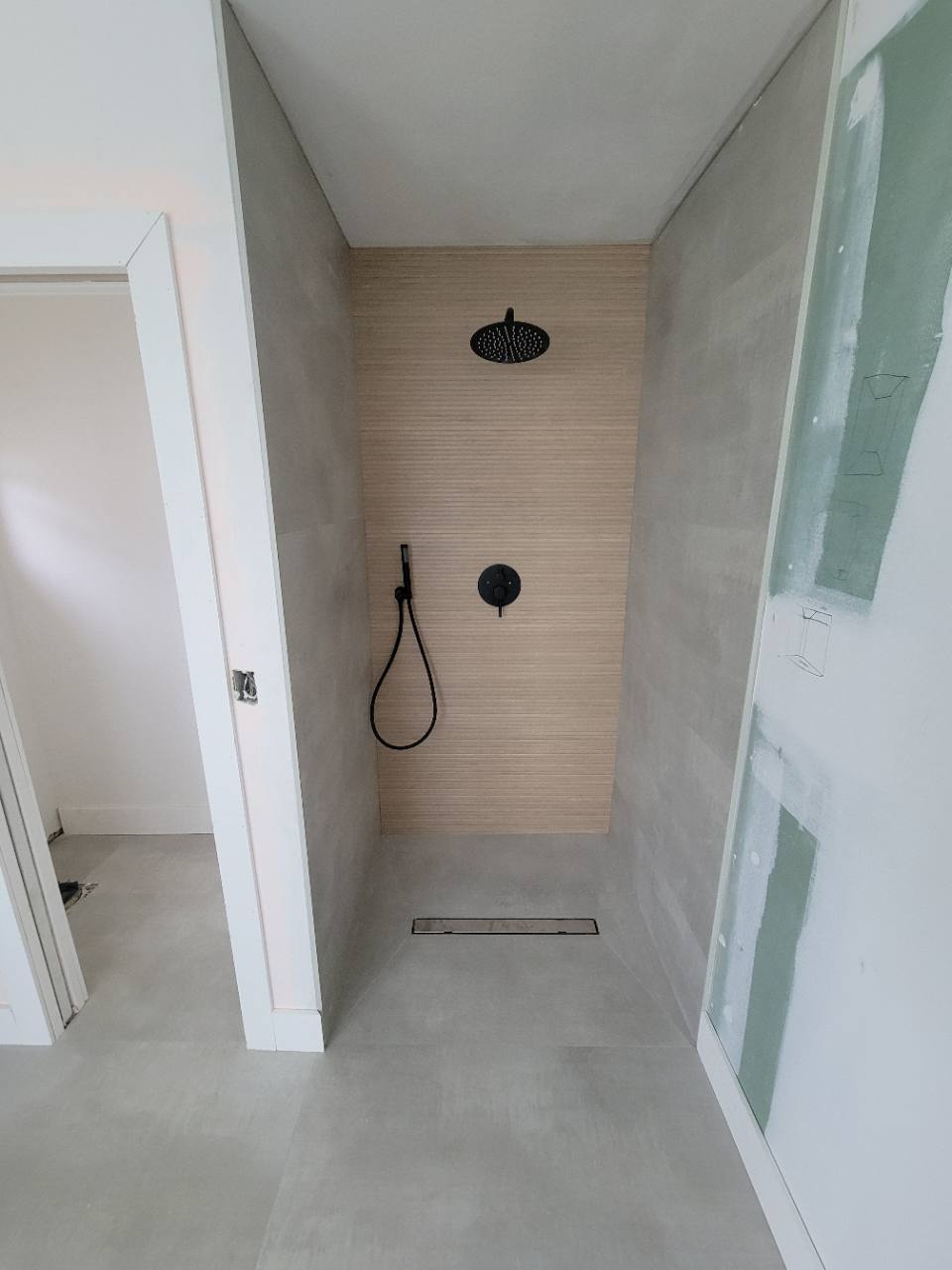 Gray shower tile and a textured accent wall during installation